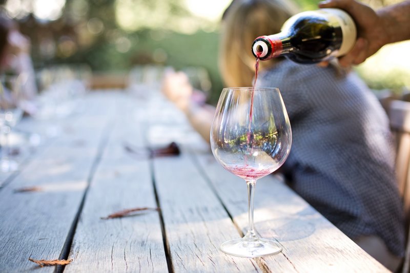 Rotwein wird aus einer Flasche in ein Glas geschenkt