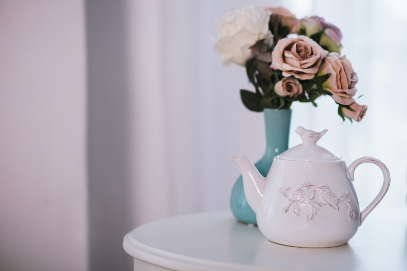 Eine weiße Keramik-Teekanne mit Blumen auf einem Tisch